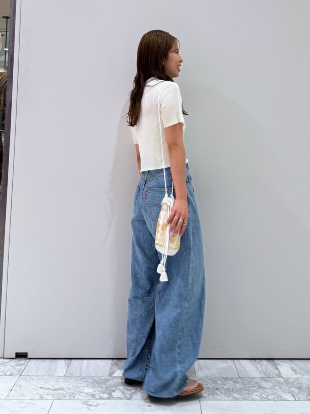 その他のサンダル、ホワイト系のハンドバッグ、ブルー系のデニムパンツを着用したレディースの夏コーディネートの4枚目の写真