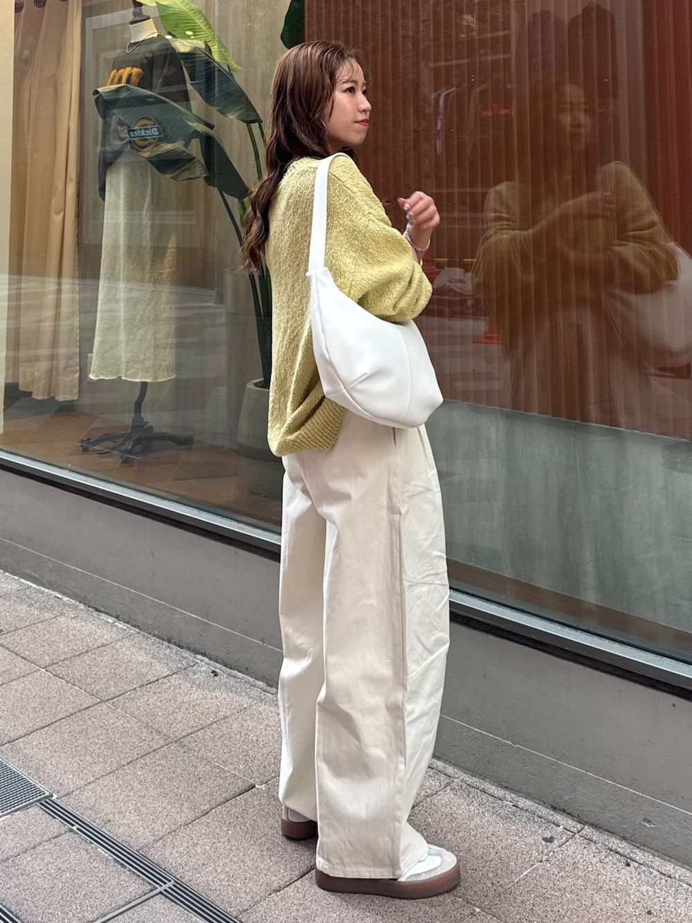 ホワイト系のチノパンツ、グリーン系のニット/セーター、ホワイト系のショルダーバッグを着用したレディースの冬コーディネートの2枚目の写真