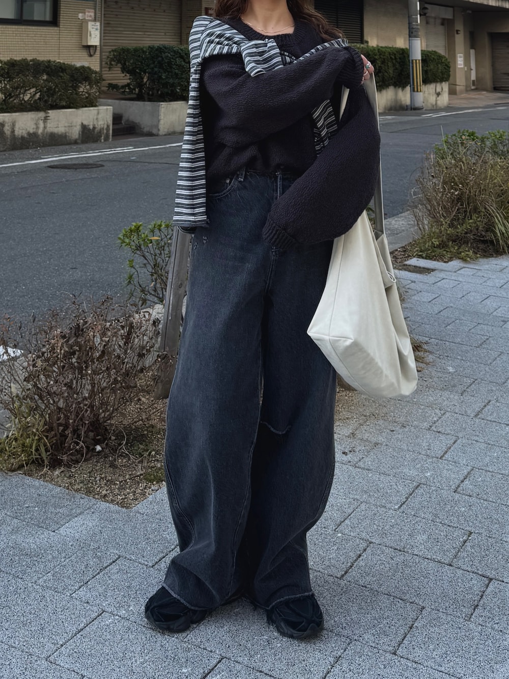 グレー系のニット/セーター、グレー系のTシャツ/カットソー、ブラック系のデニムパンツを着用したレディースの冬コーディネートの2枚目の写真