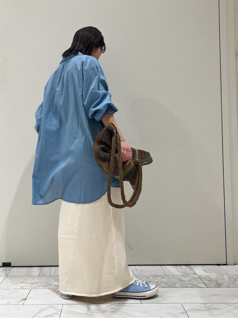 ブラウン系のトートバッグ、ホワイト系のスカート、ブルー系のシャツ/ブラウスを着用したレディースの春コーディネートの5枚目の写真