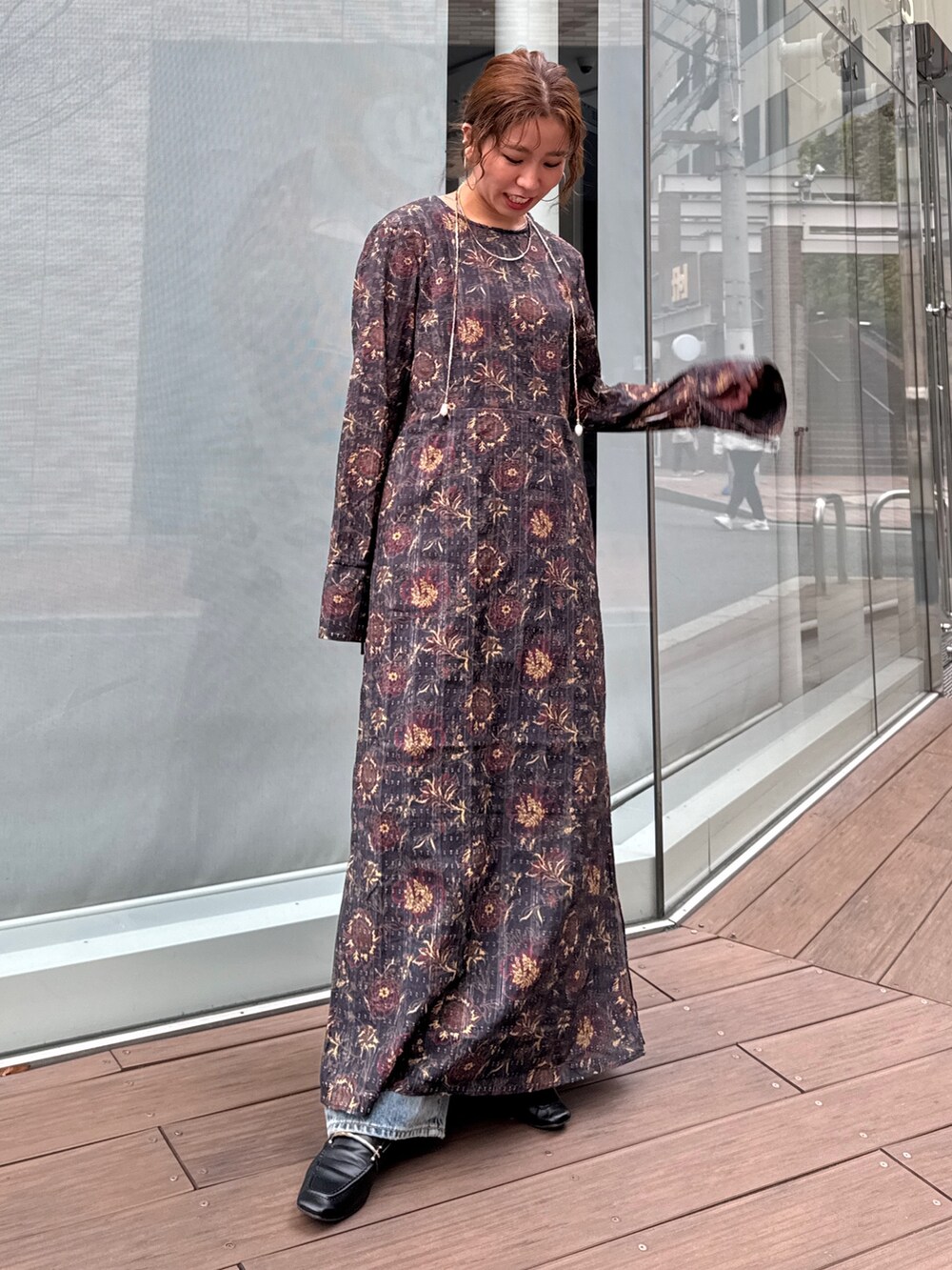 ブラック系のワンピース、ブルー系のデニムパンツ、ブラウン系のネックレスを着用したレディースの冬コーディネートの6枚目の写真