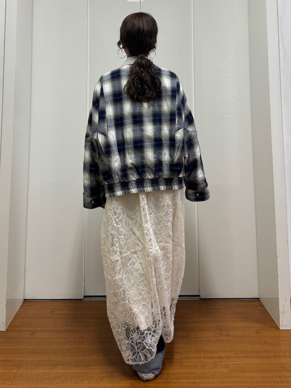 ベージュ系のブルゾン、ホワイト系のワンピース、ブルー系のデニムパンツを着用したレディースの冬コーディネートの2枚目の写真