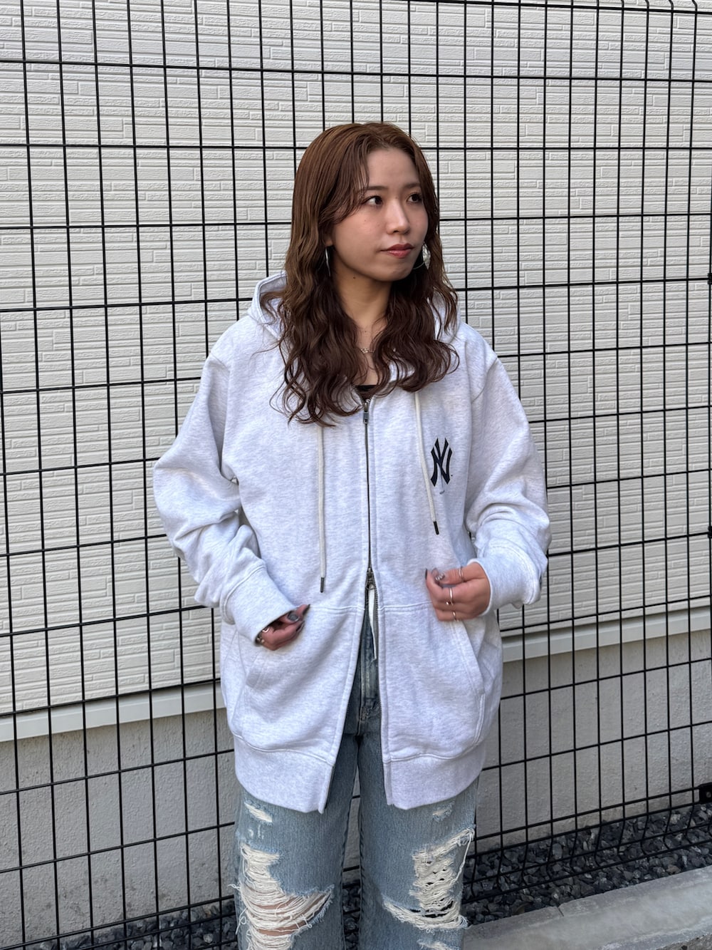 グレー系のパーカー、ブルー系のデニムパンツ、ブラック系のパンプスを着用したレディースの春コーディネートの6枚目の写真