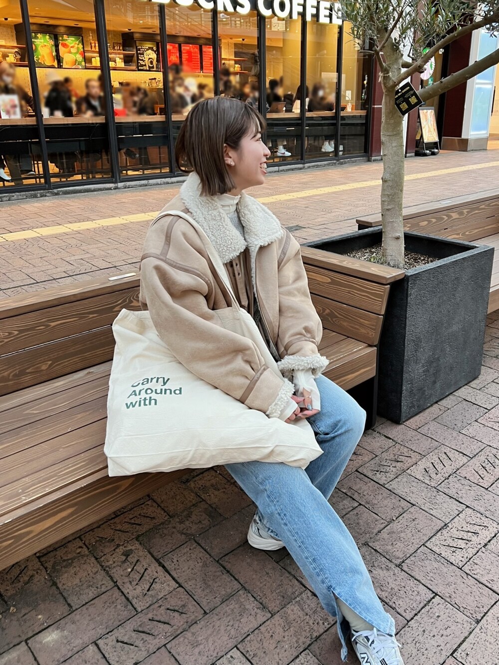 ベージュ系のムートンコート、ホワイト系のハンドバッグ、グレー系のニット/セーターを着用したレディースの冬コーディネートの7枚目の写真