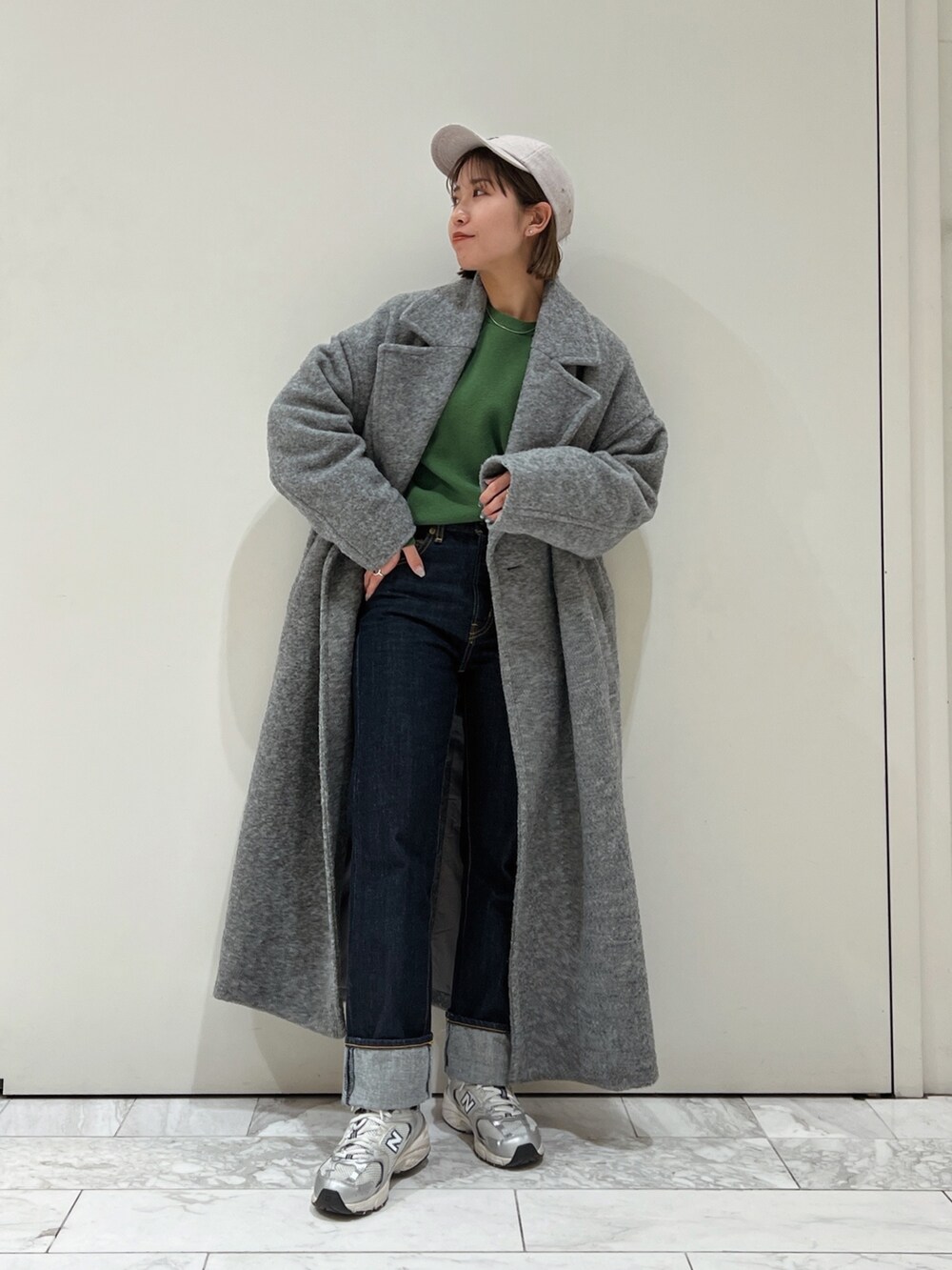 グレー系のチェスターコート、グリーン系のニット/セーター、グレー系のキャップを着用したレディースの冬コーディネートの3枚目の写真