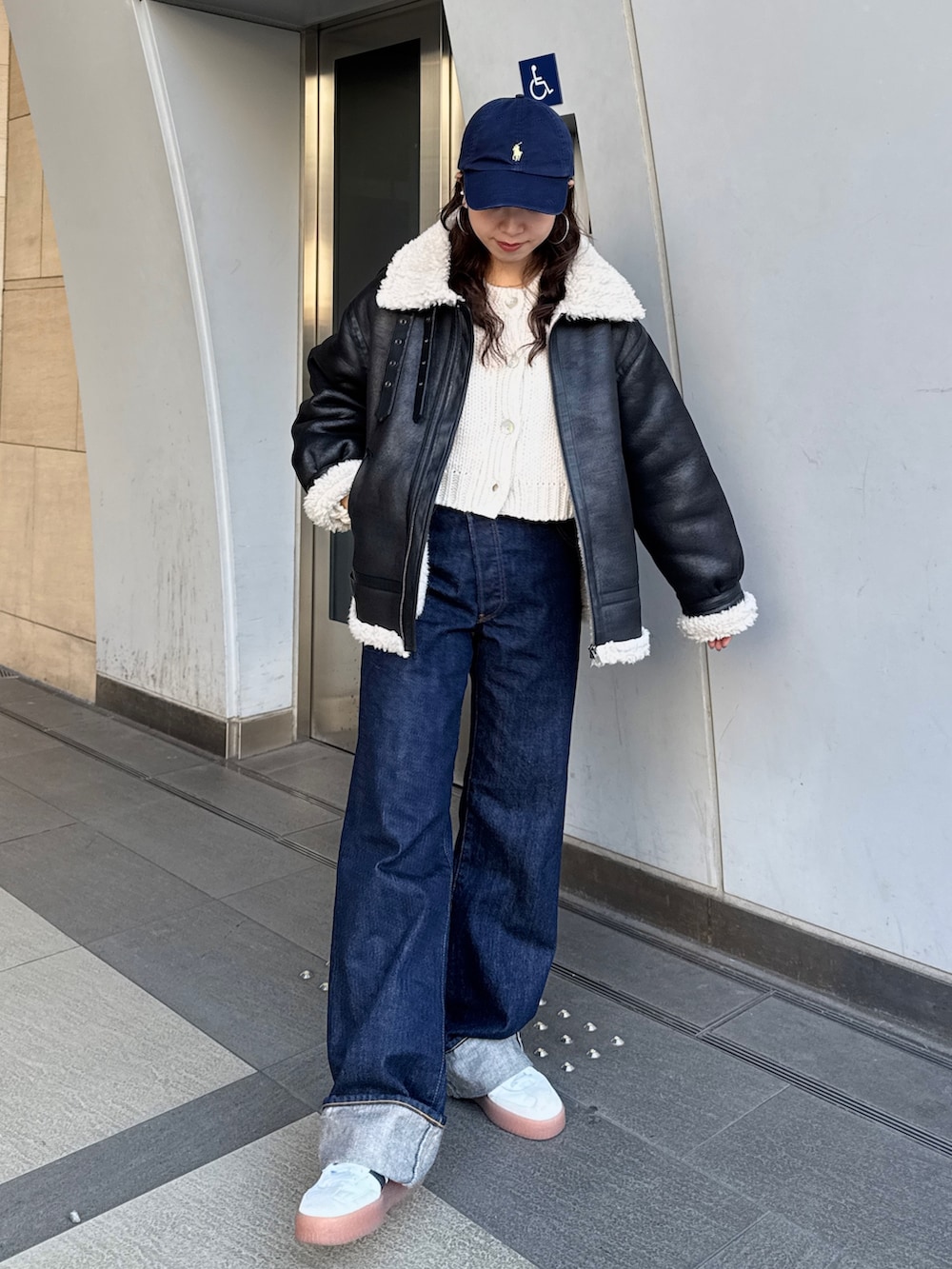 ブルー系のデニムパンツ、ホワイト系のカーディガン/ボレロ、ブラック系のブルゾンを着用したレディースの冬コーディネートの6枚目の写真