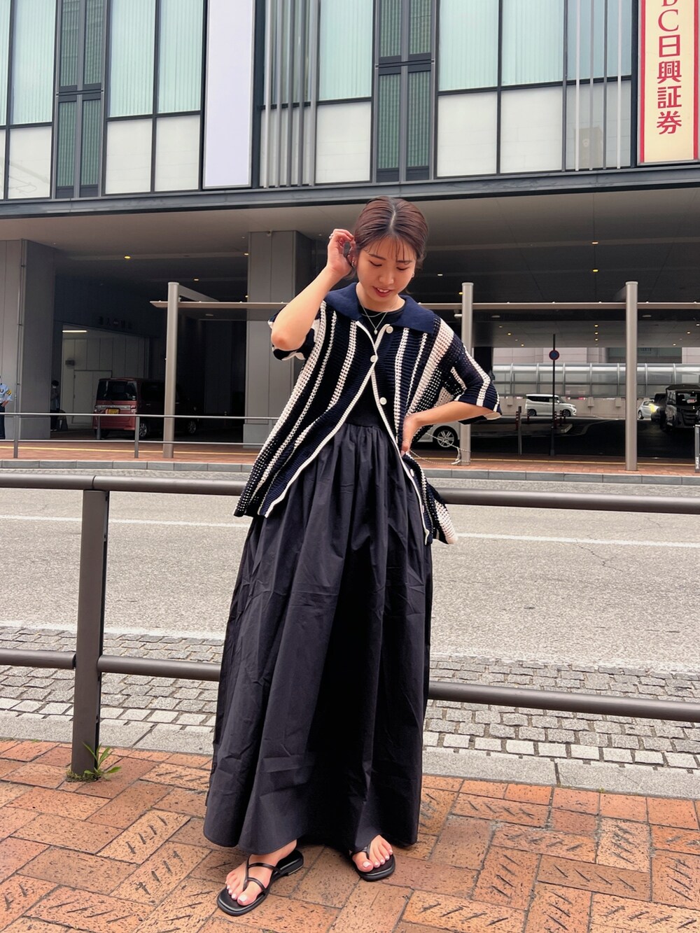 ブラック系のワンピース、ブルー系のカーディガン/ボレロ、ブラック系のサンダルを着用したレディースの春コーディネートの5枚目の写真