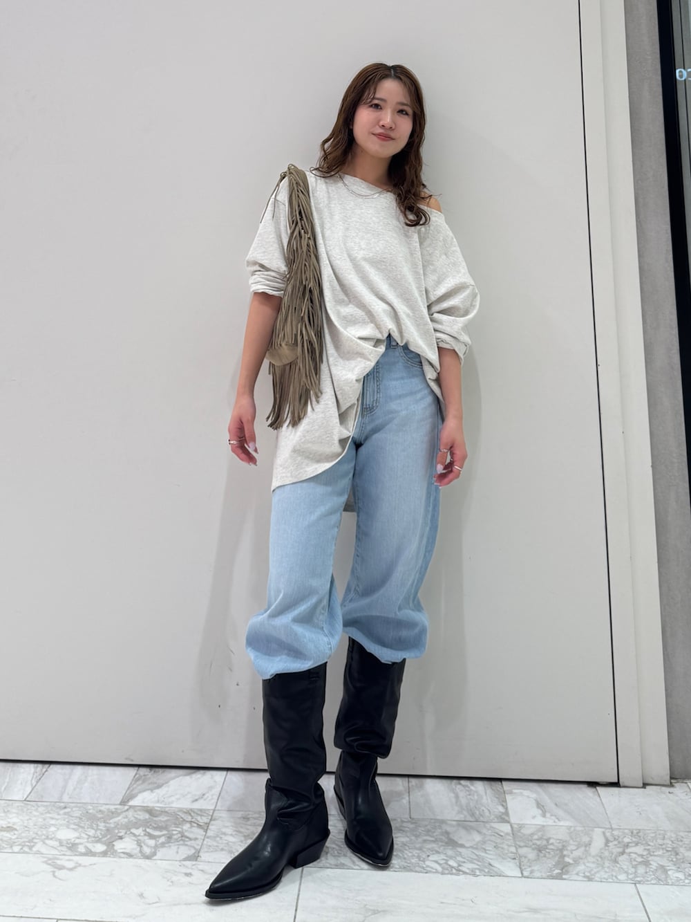 グレー系のTシャツ/カットソー、ベージュ系のハンドバッグ、ブルー系のデニムパンツを着用したレディースの春コーディネートの2枚目の写真