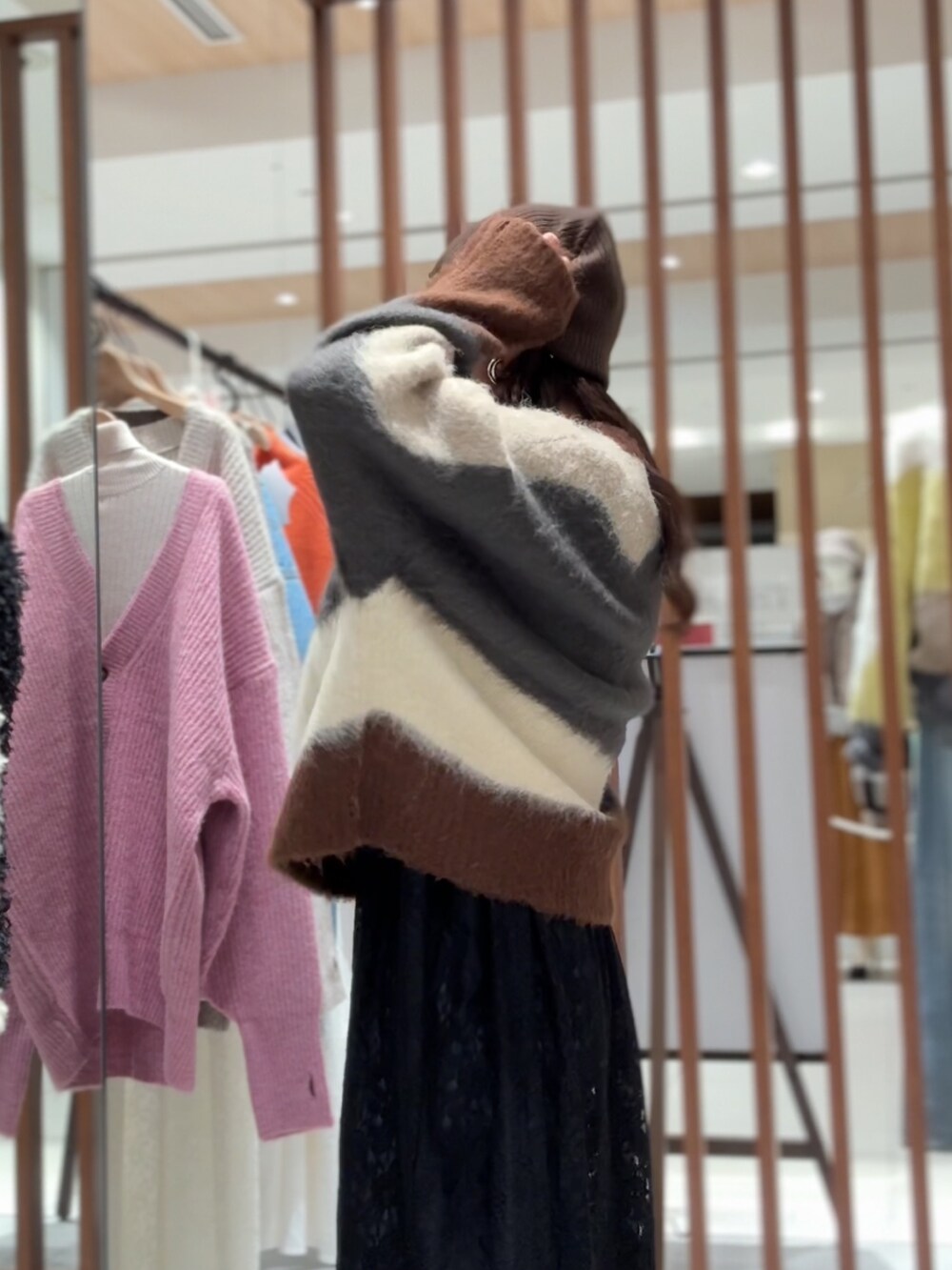 グレー系のニット/セーター、ブラック系のワンピース、ブルー系のデニムパンツを着用したレディースの秋コーディネートの6枚目の写真