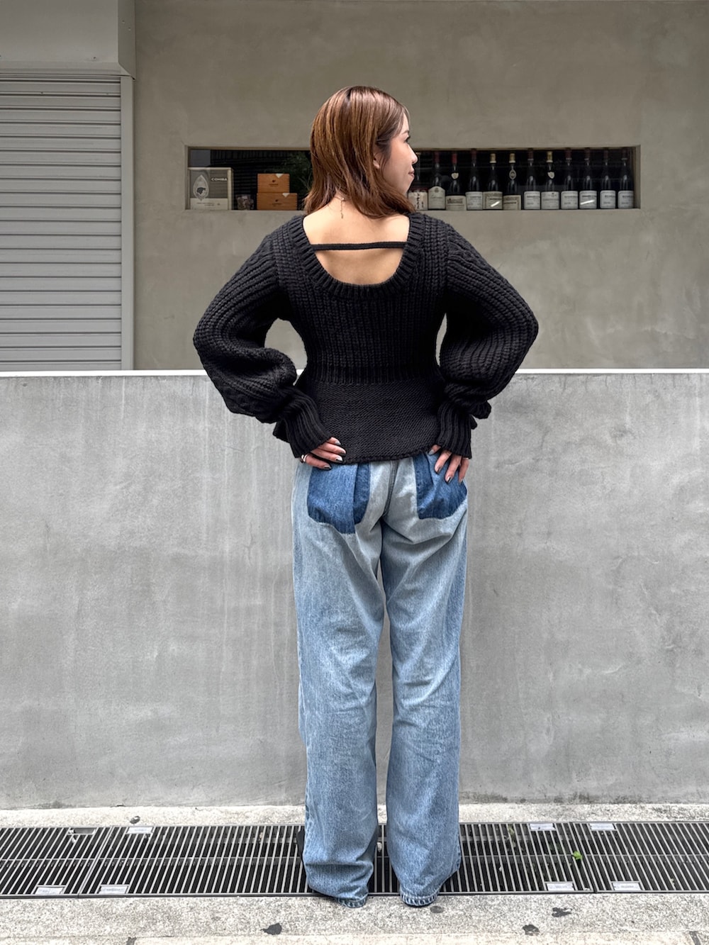 ブラック系のニット/セーター、ブルー系のデニムパンツ、ブラック系のサンダルを着用したレディースの秋コーディネートの3枚目の写真