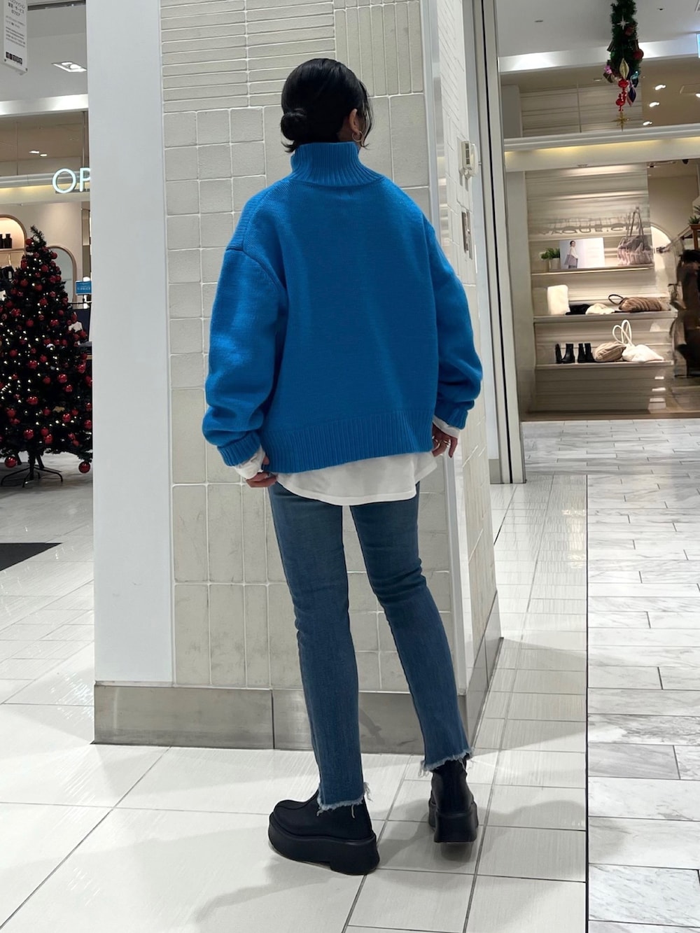 ブルー系のニット/セーター、ホワイト系のTシャツ/カットソー、ブラック系のブーツを着用したレディースの秋コーディネートの7枚目の写真