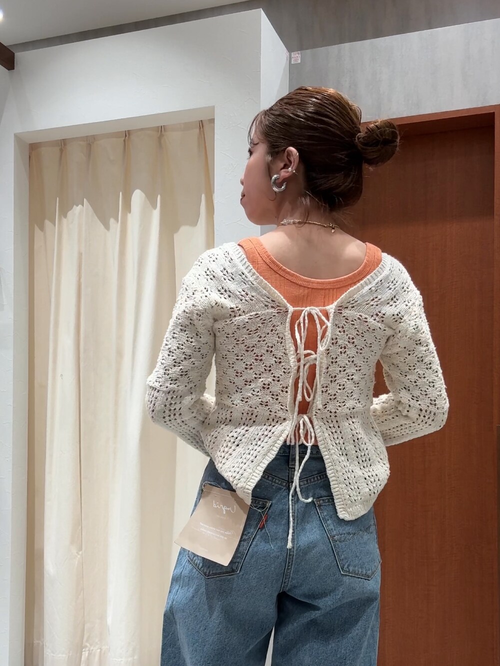 ブルー系のデニムパンツ、オレンジ系のタンクトップ、ホワイト系のカーディガン/ボレロを着用したレディースの春コーディネートの10枚目の写真