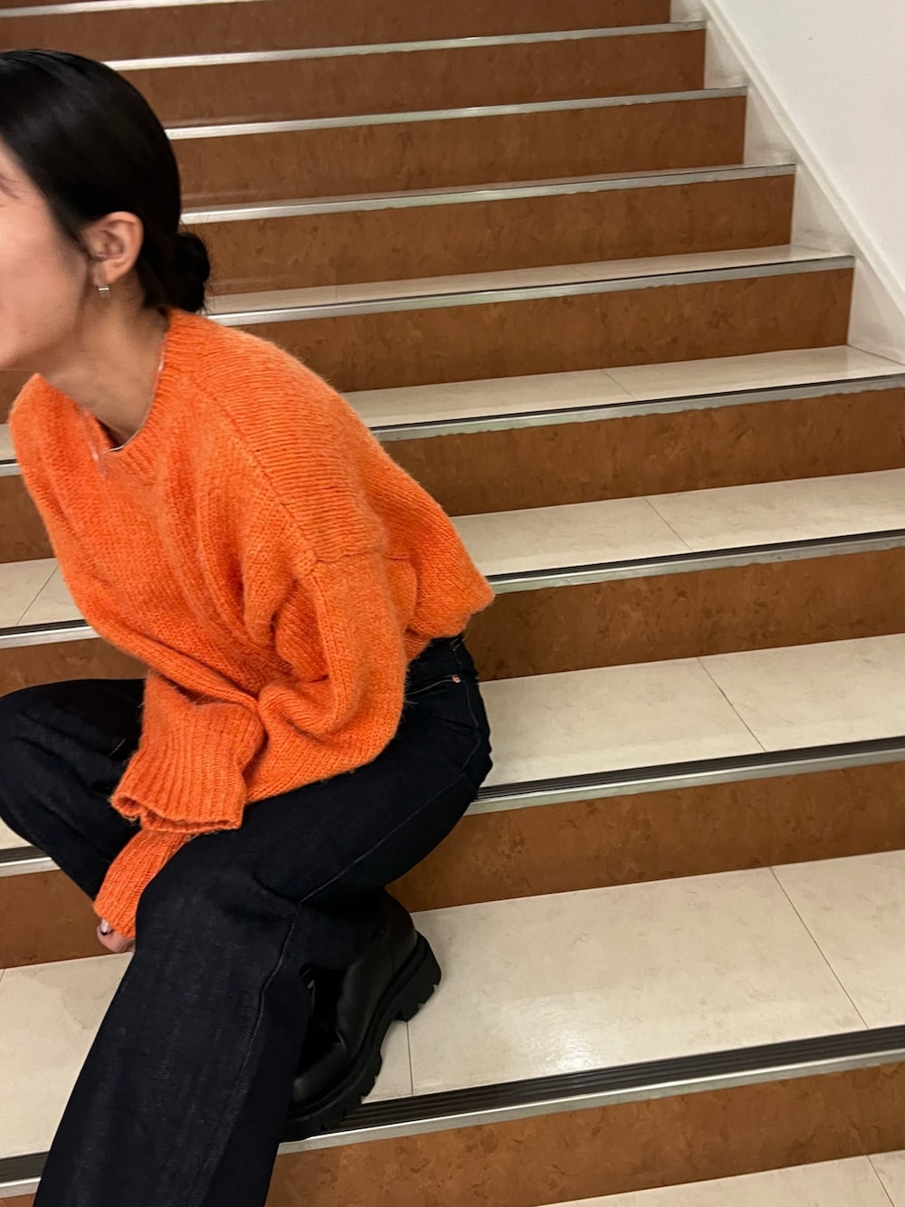 オレンジ系のニット/セーター、ブルー系のデニムパンツ、ホワイト系のダウンジャケット/コートを着用したレディースの秋コーディネートの10枚目の写真