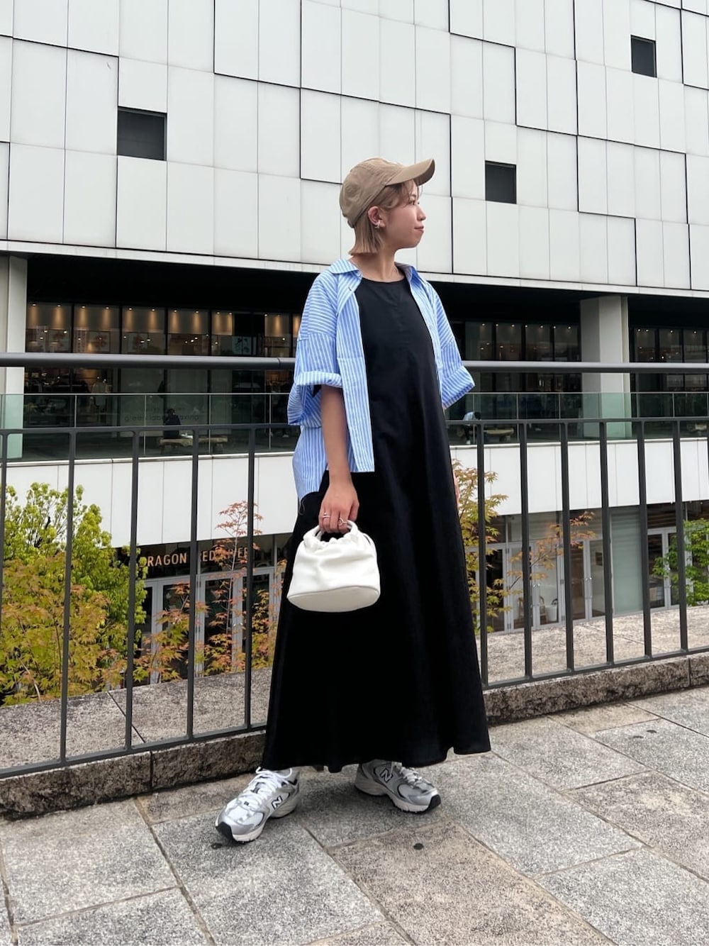 ブラック系のワンピース、ブルー系のシャツ/ブラウス、ホワイト系のハンドバッグを着用したレディースの春コーディネートの2枚目の写真