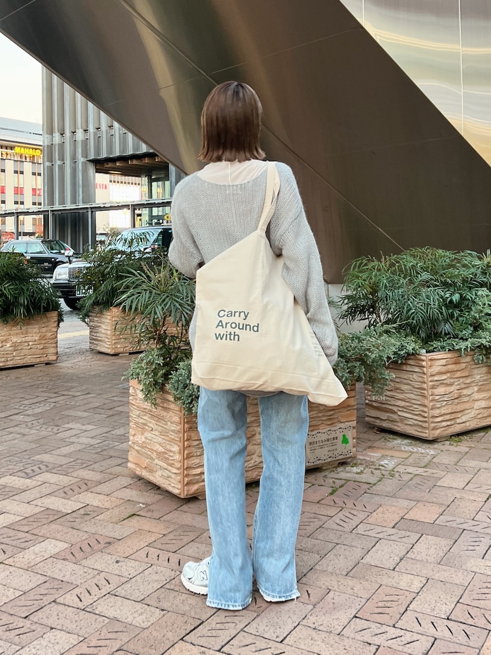 ベージュ系のムートンコート、ホワイト系のハンドバッグ、グレー系のニット/セーターを着用したレディースの冬コーディネートの9枚目の写真