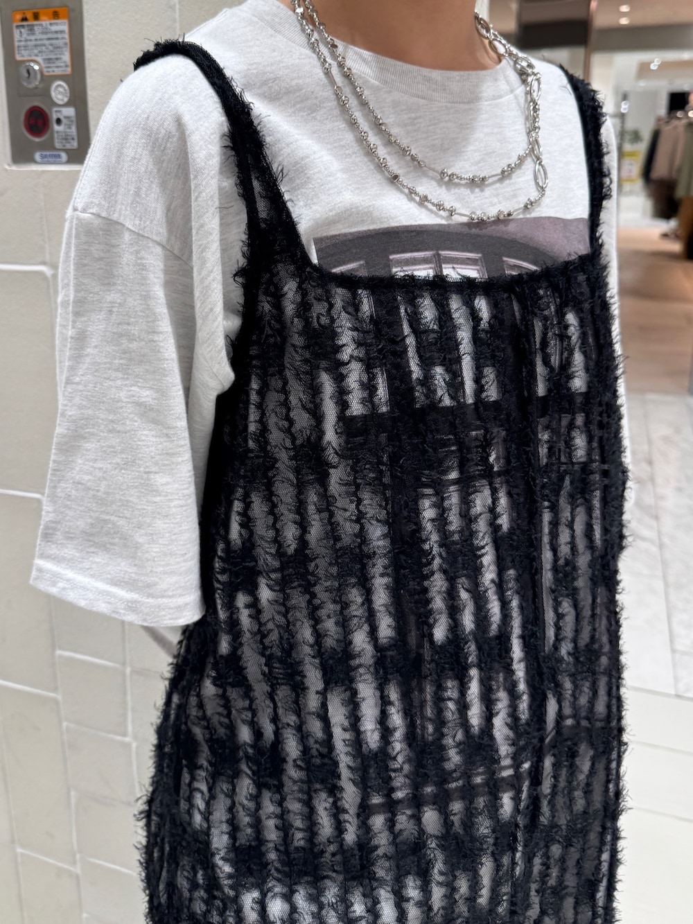 ブラック系のワンピース、グレー系のTシャツ/カットソー、ブルー系のデニムパンツを着用したレディースの春コーディネートの10枚目の写真