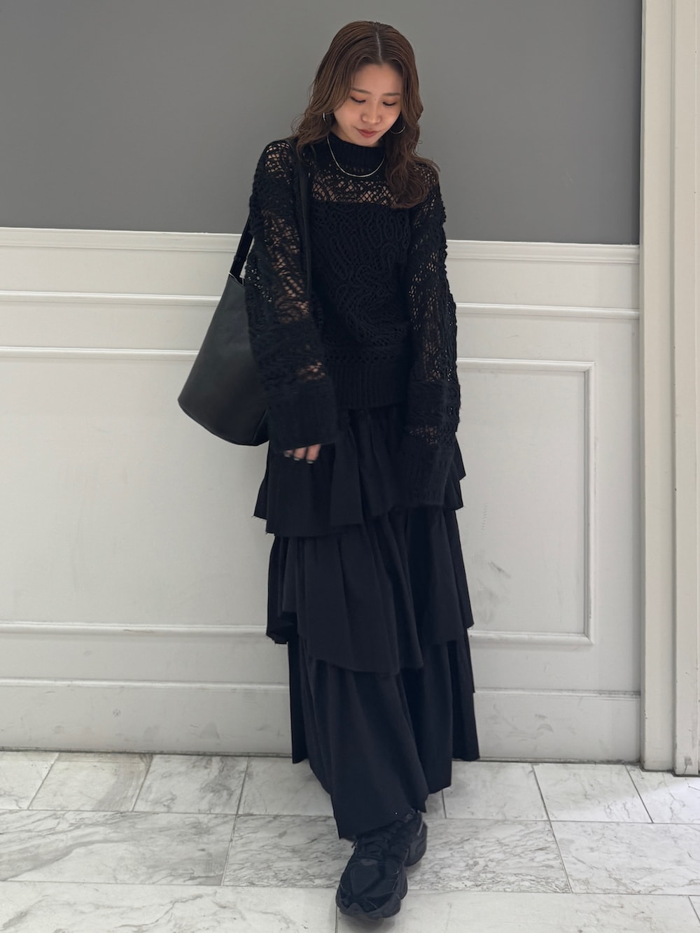 ブラック系のスカート、ブラック系のニット/セーター、ブラック系のショルダーバッグを着用したレディースの冬コーディネートの5枚目の写真