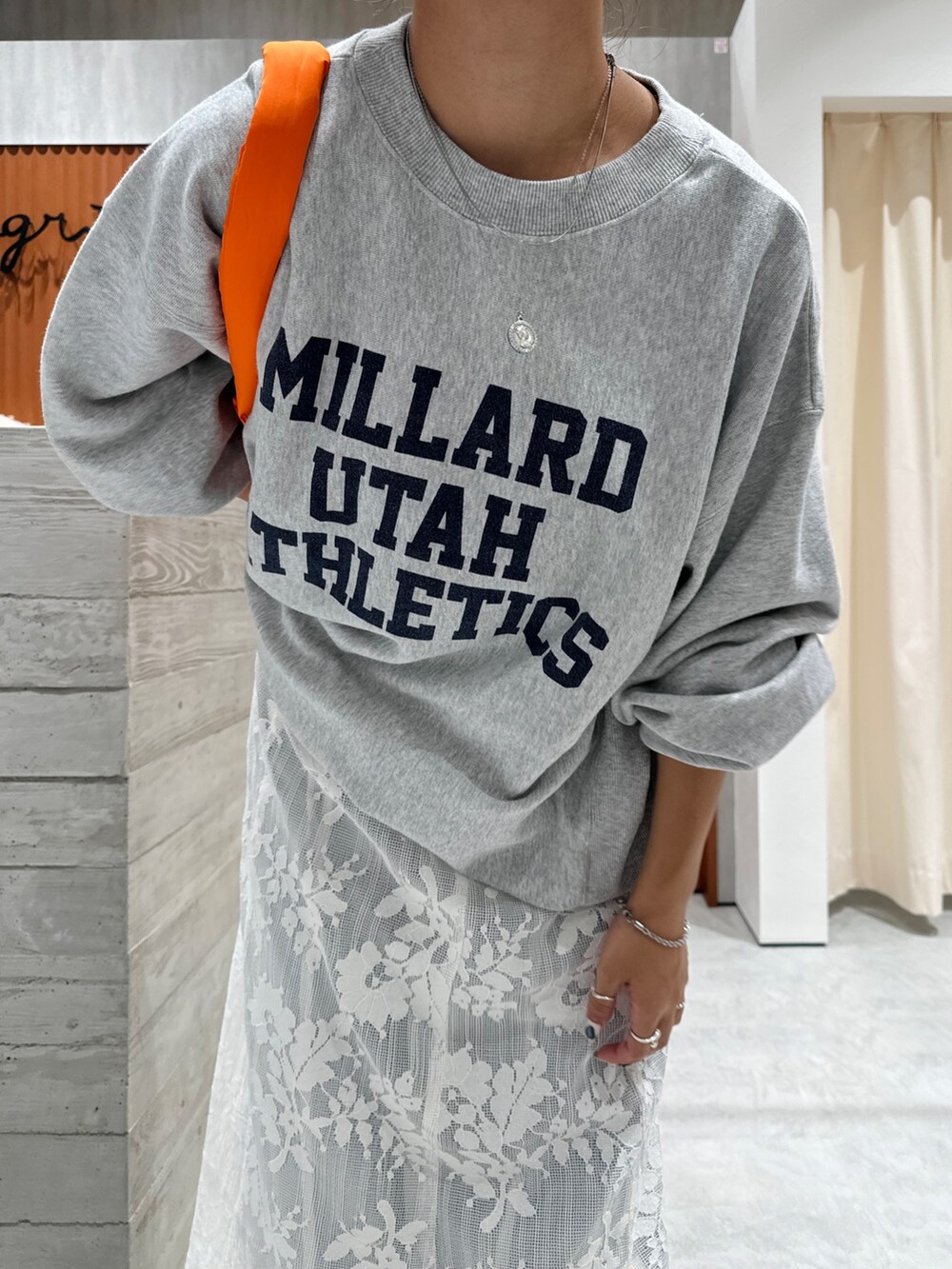 ホワイト系のワンピース、グレー系のスウェット、ブルー系のデニムパンツを着用したレディースの秋コーディネートの7枚目の写真