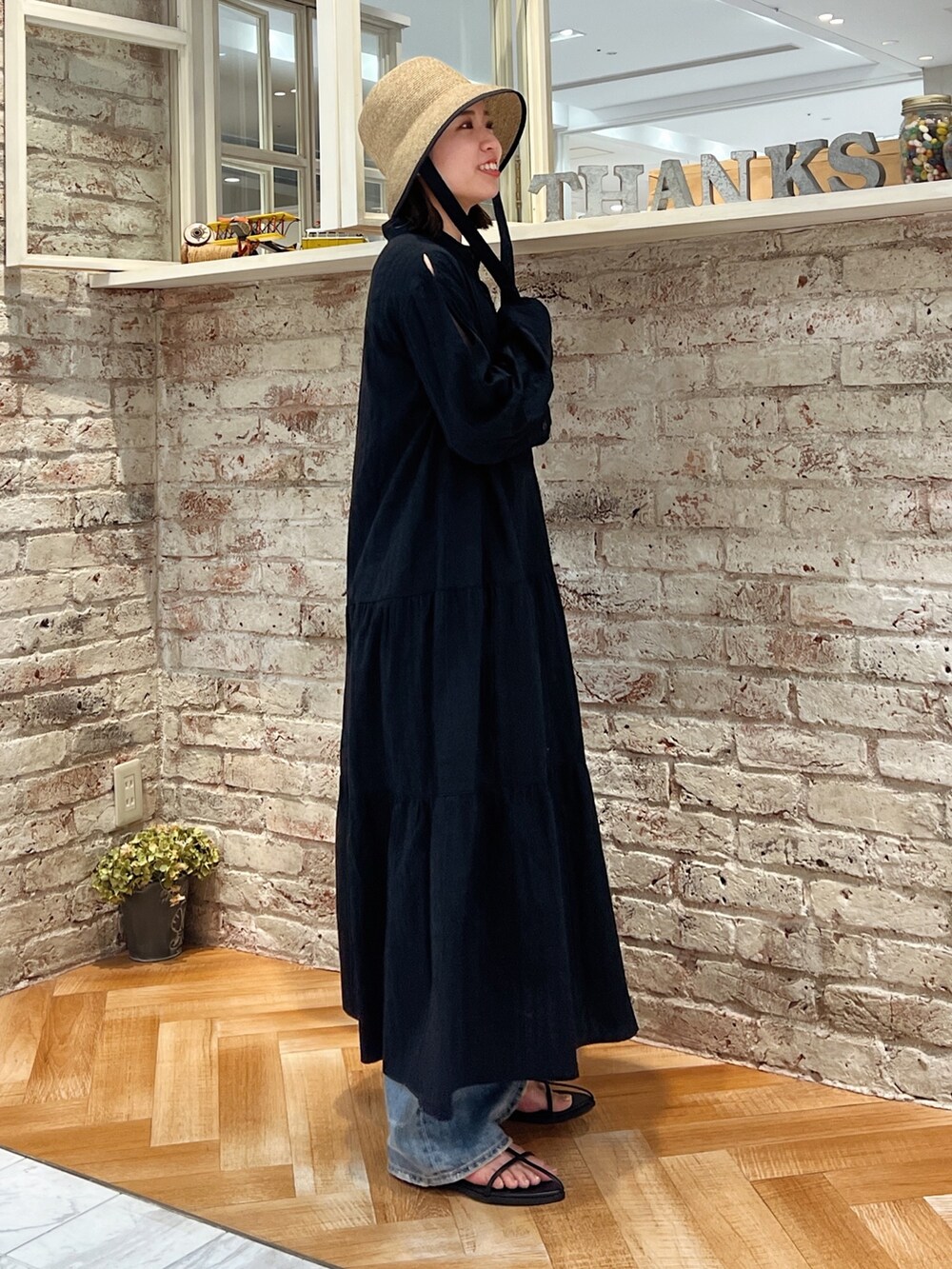 ブルー系のデニムパンツ、ブラック系のサンダル、ブラック系のワンピースを着用したレディースの春コーディネートの6枚目の写真