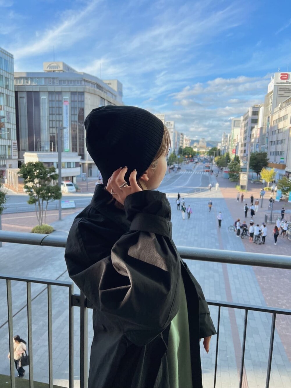 ブラック系のステンカラーコート、グリーン系のワンピース、ブラック系のブーツを着用したレディースの秋コーディネートの8枚目の写真