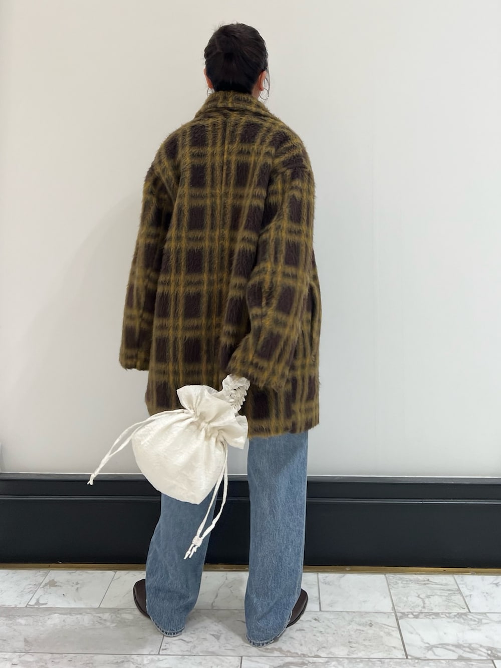 レッド系のニット/セーター、ホワイト系のハンドバッグ、ブルー系のデニムパンツを着用したレディースの冬コーディネートの4枚目の写真