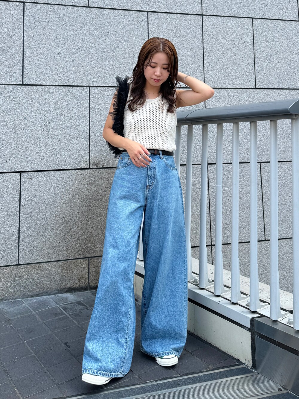 ブルー系のデニムパンツ、ホワイト系のニット/セーター、ブラック系のショルダーバッグを着用したレディースの秋コーディネートの2枚目の写真