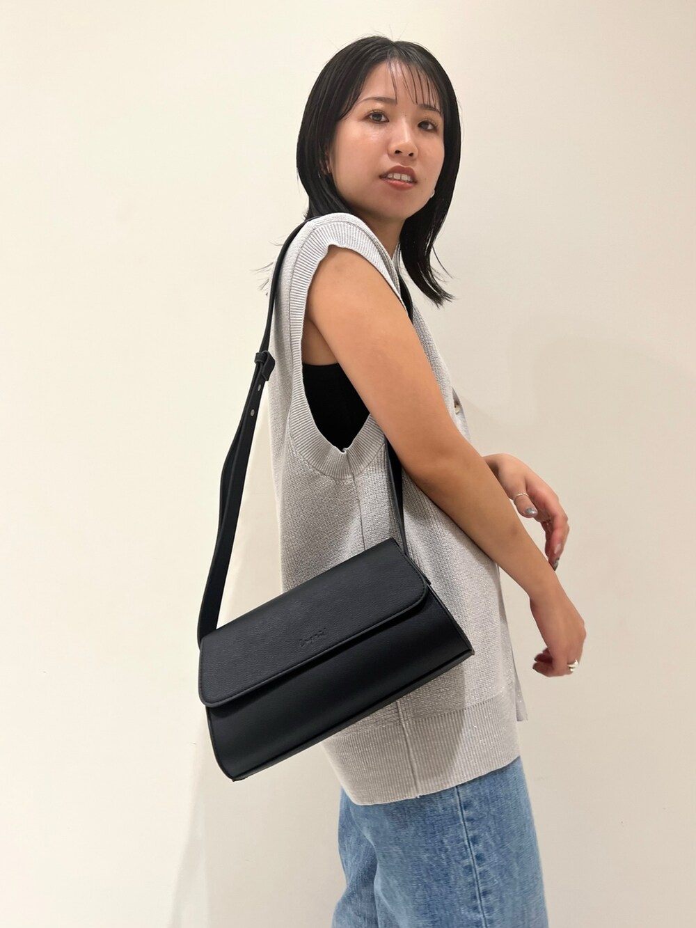 ブルー系のデニムパンツ、ブラック系のショルダーバッグ、シルバー系のベストを着用したレディースの夏コーディネートの7枚目の写真