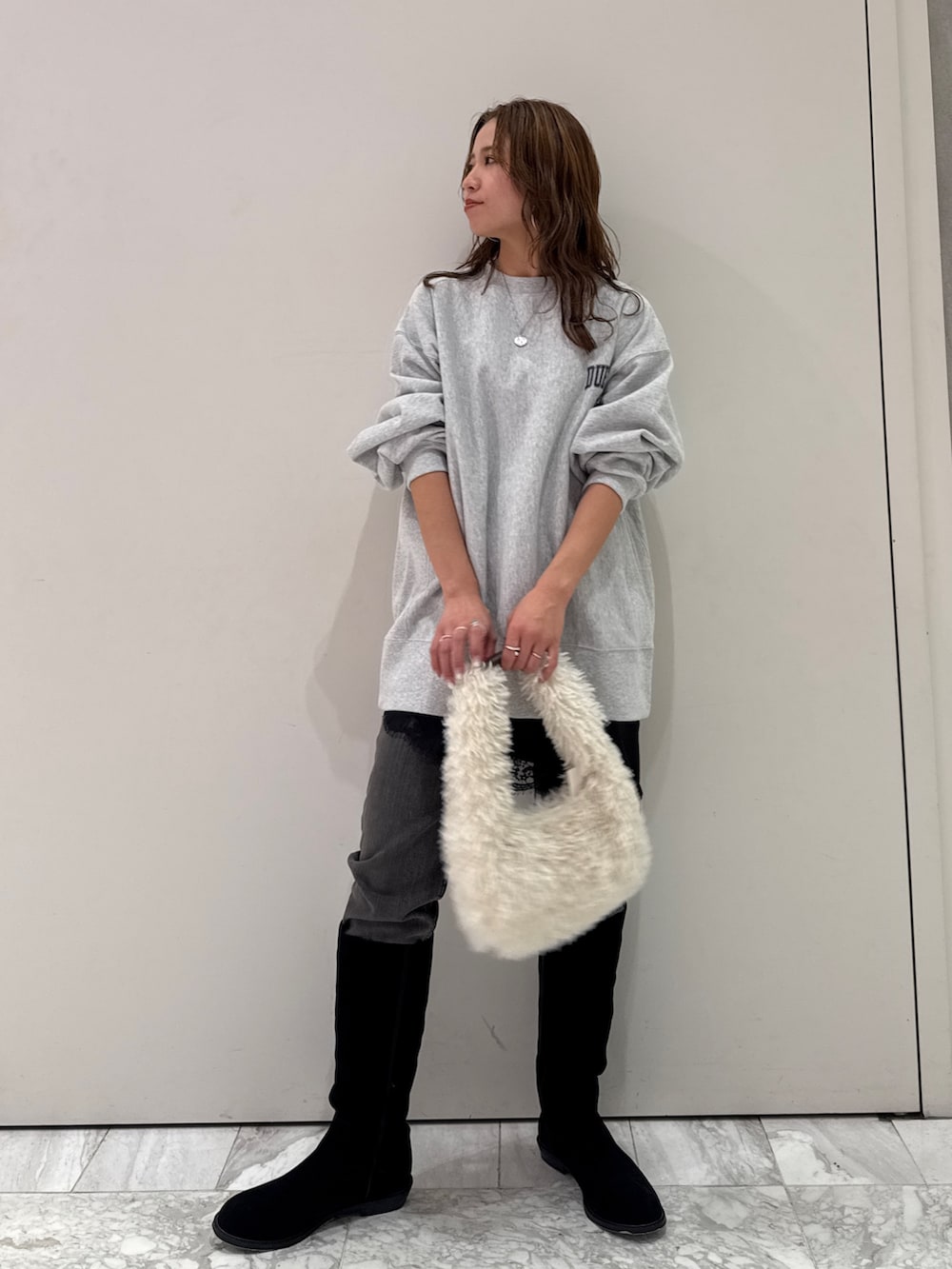 グレー系のスウェット、ブラック系のキャミソール、ブラック系のデニムパンツを着用したレディースの冬コーディネートの7枚目の写真