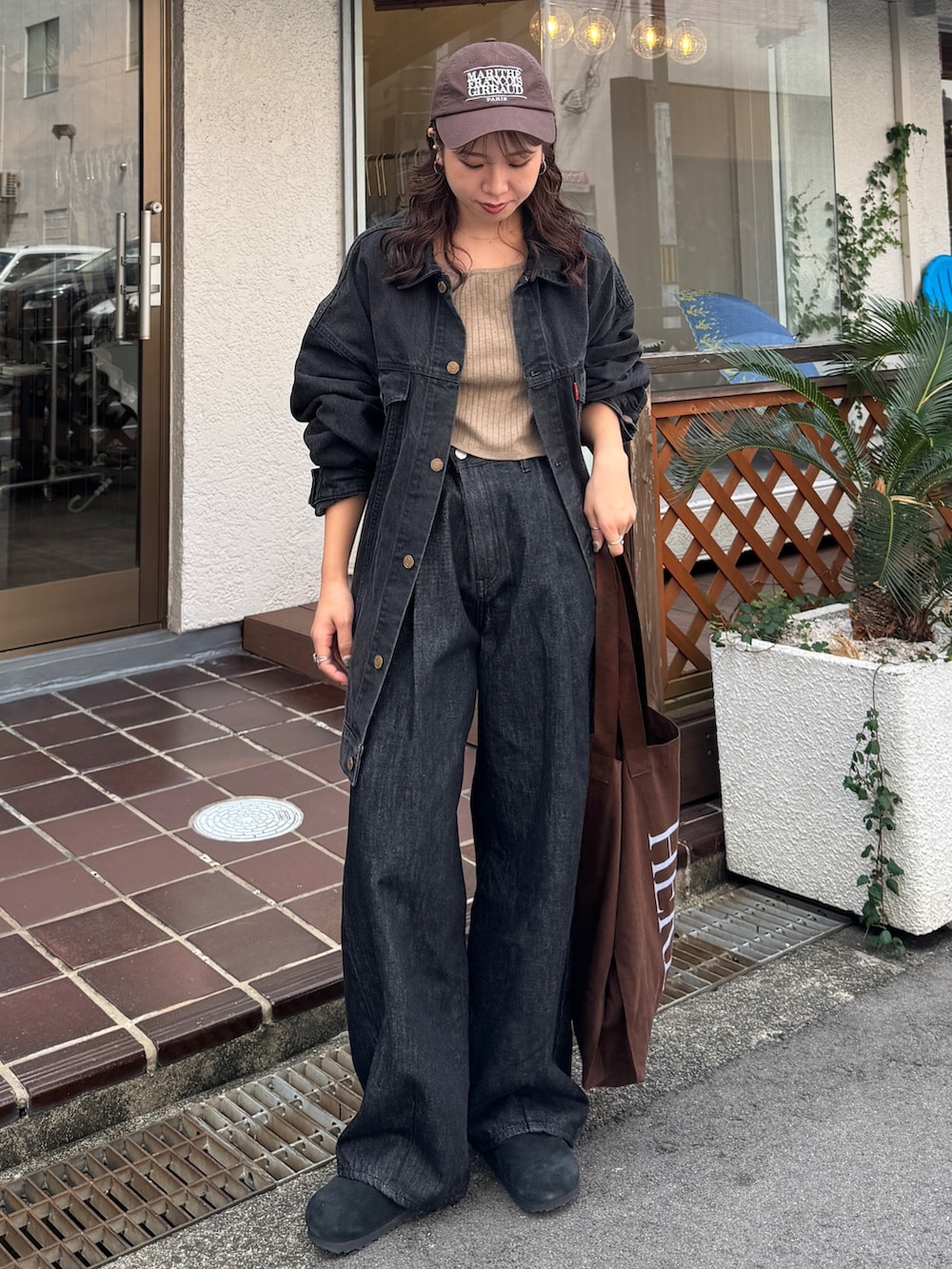 ブラック系のデニムジャケット、ブラック系のデニムパンツ、ブラウン系のトートバッグを着用したレディースの秋コーディネートの2枚目の写真