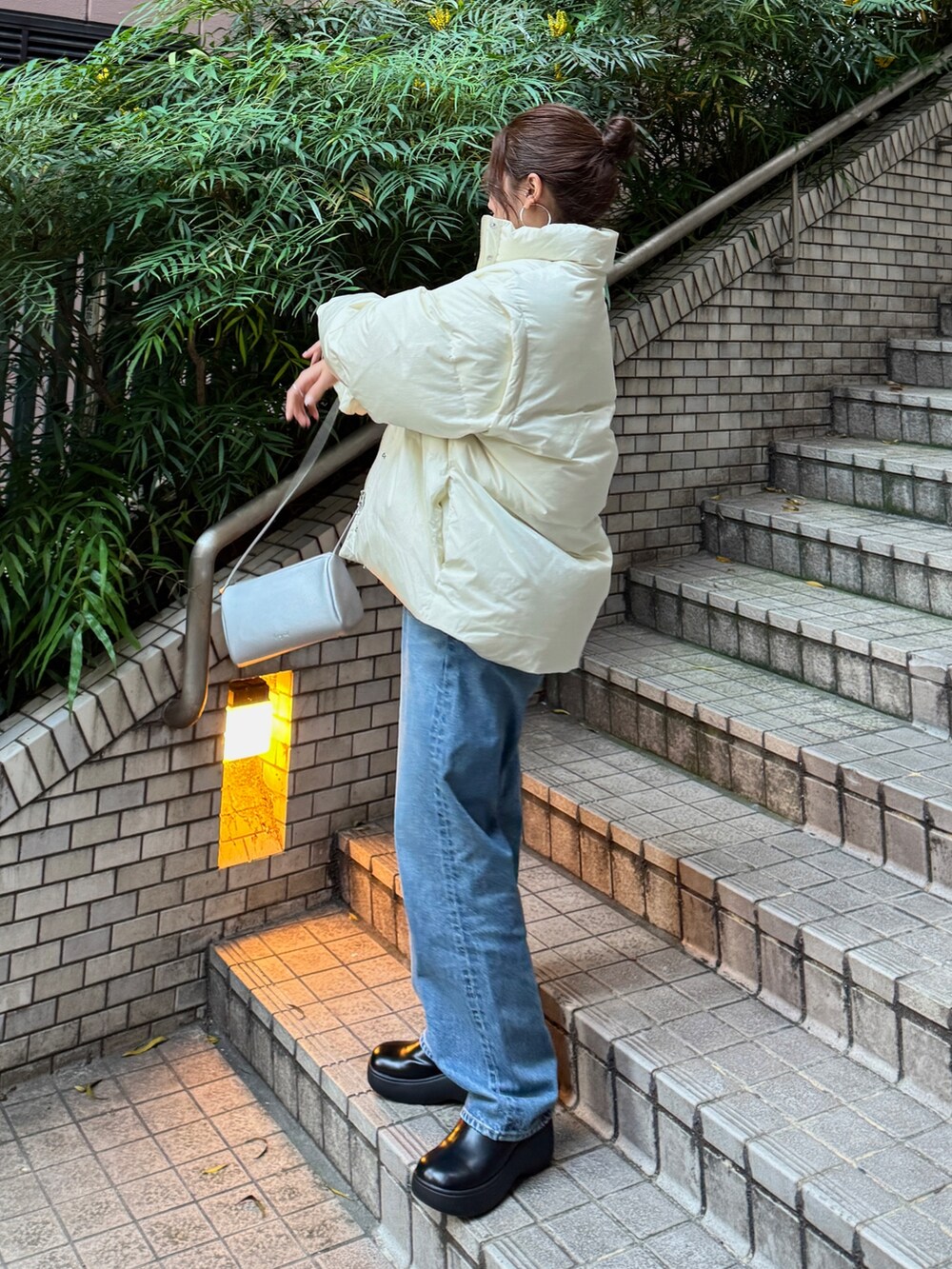 オレンジ系のニット/セーター、ホワイト系のダウンジャケット/コート、ブルー系のデニムパンツを着用したレディースの冬コーディネートの3枚目の写真