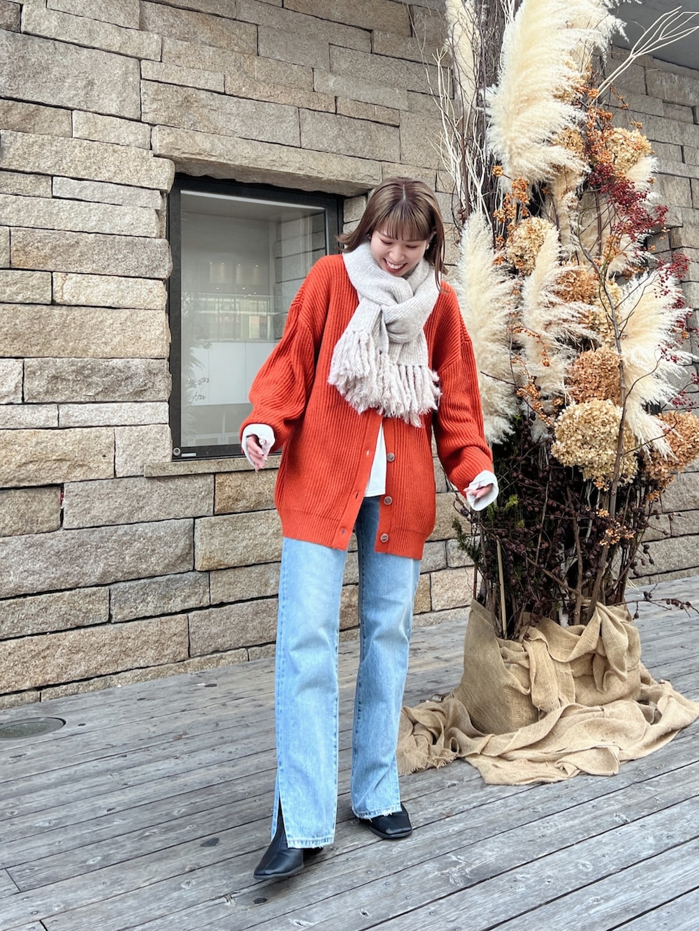 オレンジ系のカーディガン/ボレロ、ブルー系のデニムパンツを着用したレディースの秋コーディネートの2枚目の写真