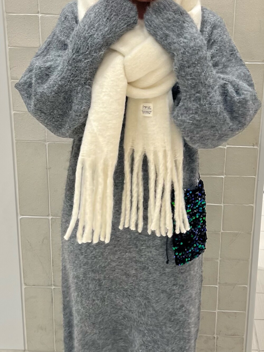 グレー系のワンピース、グリーン系のショルダーバッグ、ホワイト系のマフラーを着用したレディースの秋コーディネートの3枚目の写真