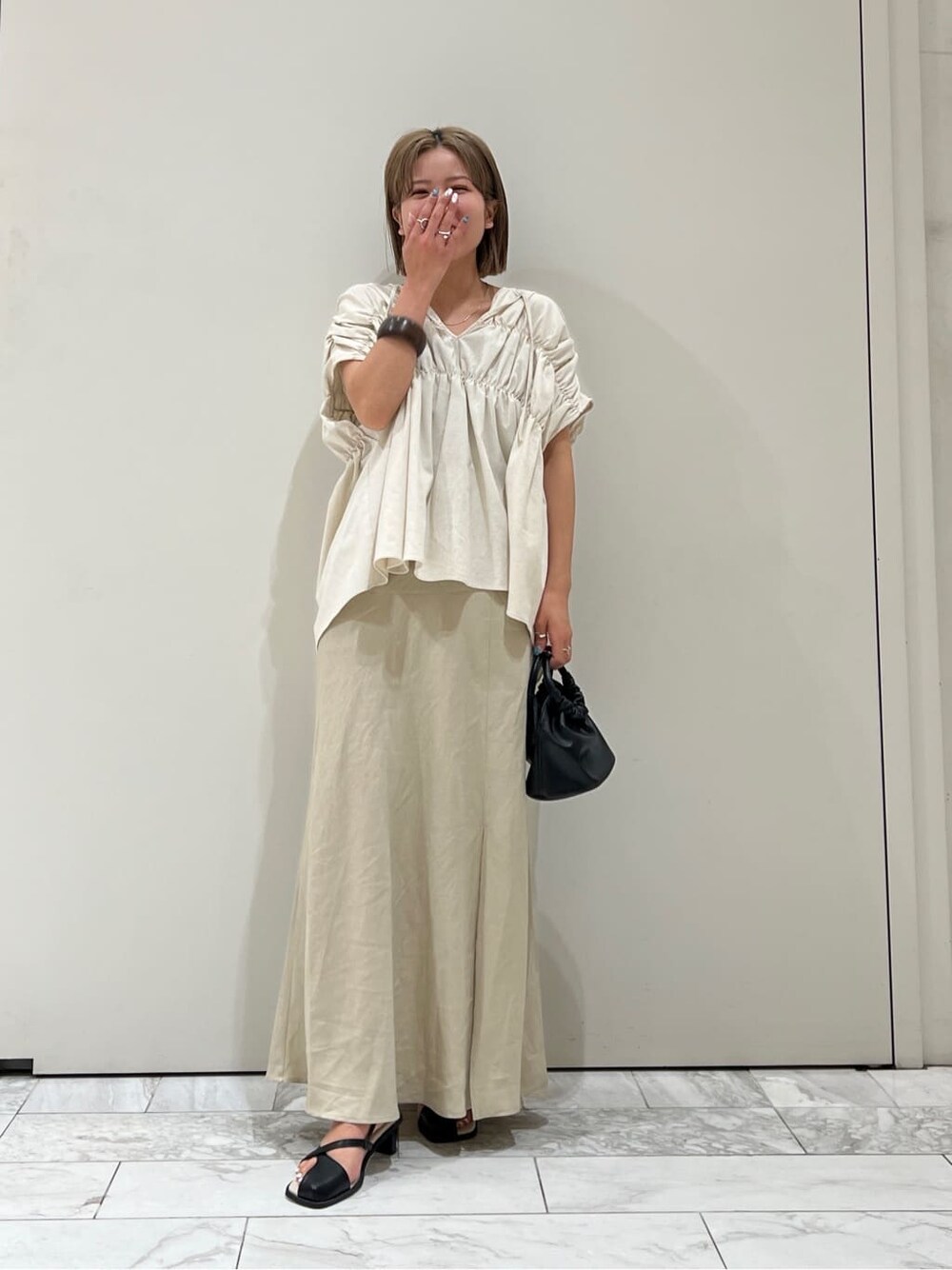 ブラック系のサンダル、ベージュ系のスカート、ホワイト系のシャツ/ブラウスを着用したレディースの夏コーディネートの7枚目の写真