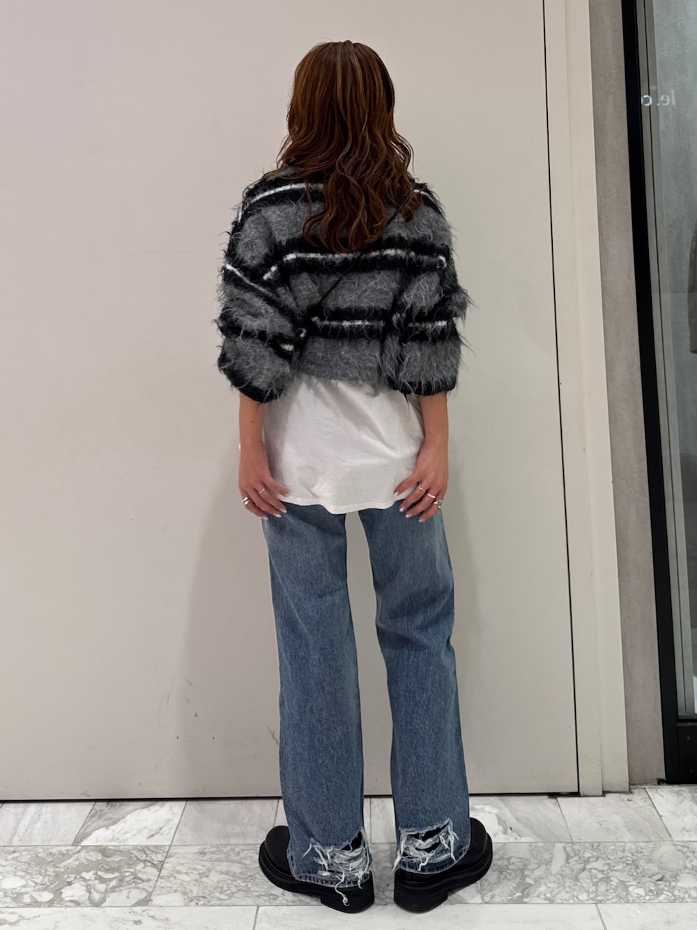 ブラック系のニット/セーター、ホワイト系のTシャツ/カットソー、ブルー系のデニムパンツを着用したレディースの冬コーディネートの4枚目の写真