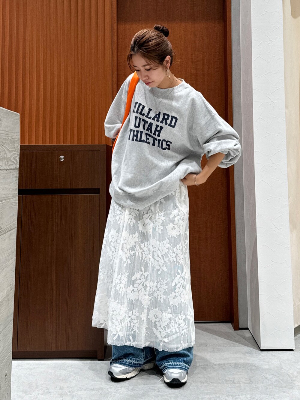 ホワイト系のワンピース、グレー系のスウェット、ブルー系のデニムパンツを着用したレディースの秋コーディネートの2枚目の写真