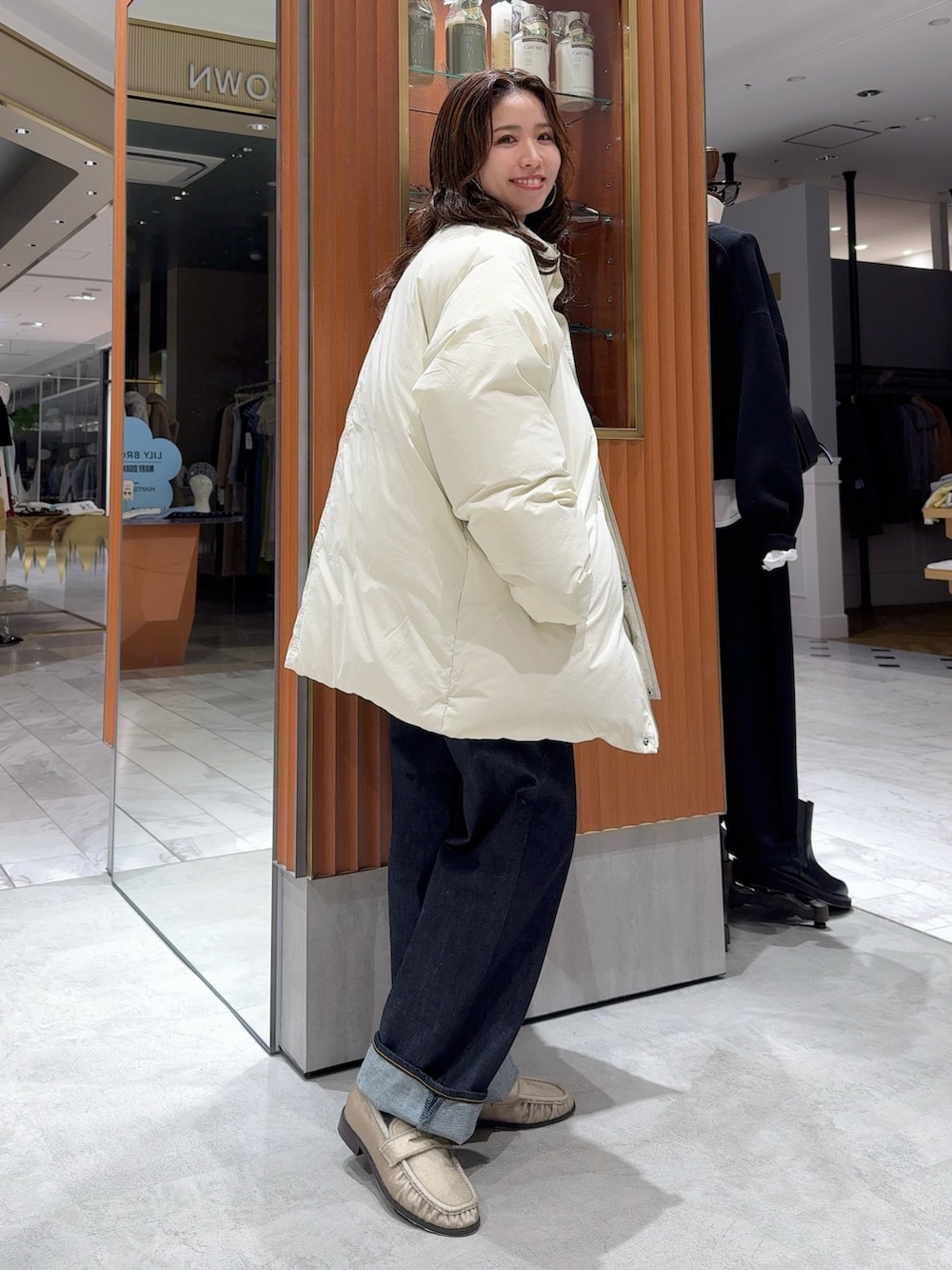 ホワイト系のダウンジャケット/コート、グレー系のニット/セーター、ブルー系のデニムパンツを着用したレディースの冬コーディネートの2枚目の写真