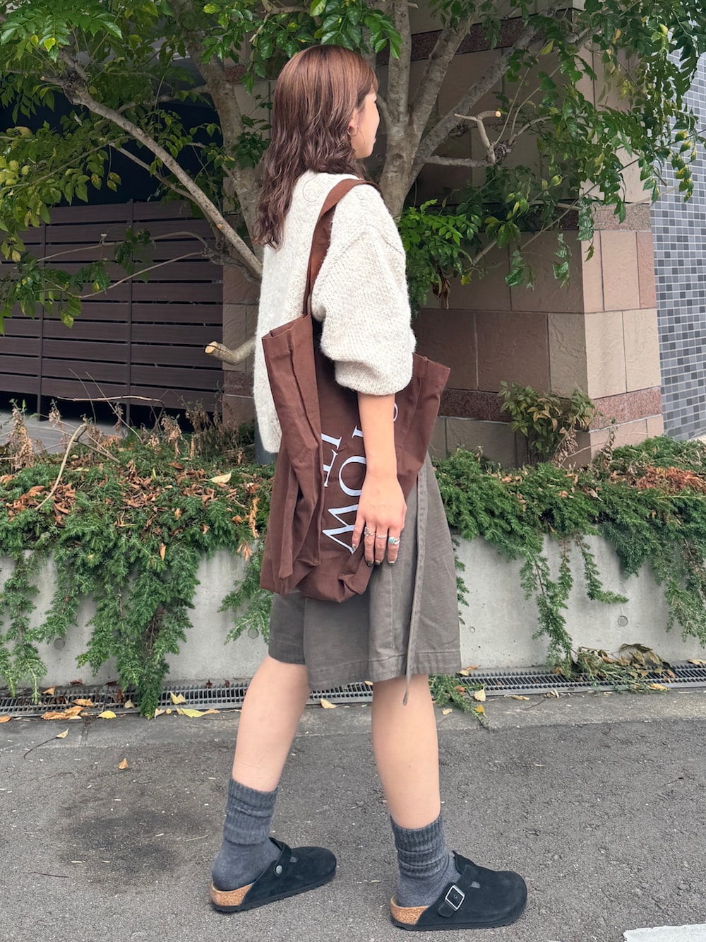 グレー系のチノパンツ、ホワイト系のニット/セーター、ブラウン系のトートバッグを着用したレディースの秋コーディネートの4枚目の写真