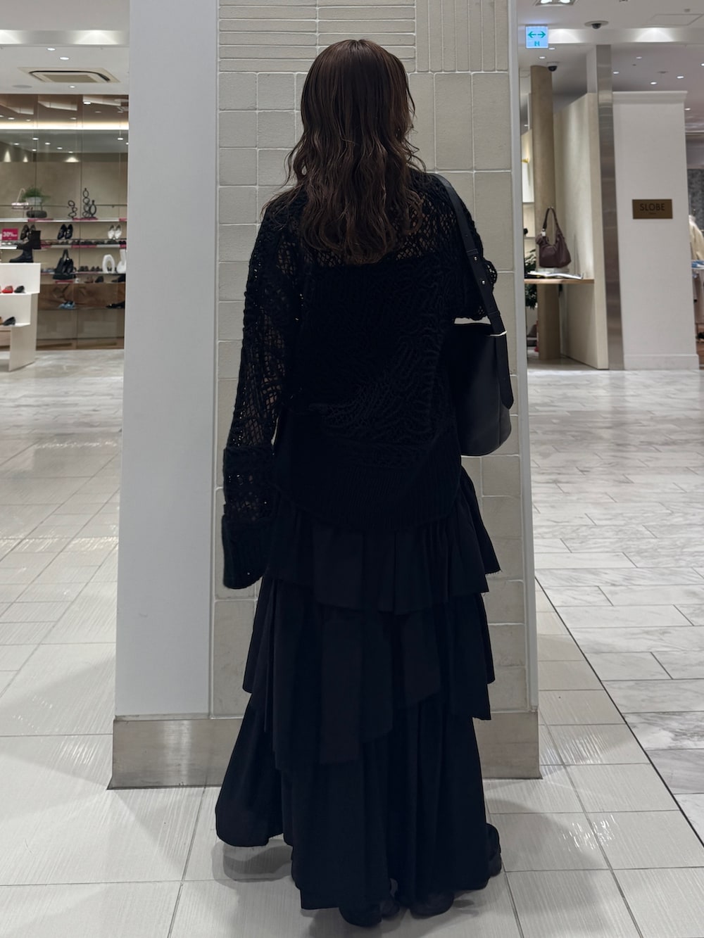 ブラック系のスカート、ブラック系のニット/セーター、ブラック系のショルダーバッグを着用したレディースの冬コーディネートの3枚目の写真