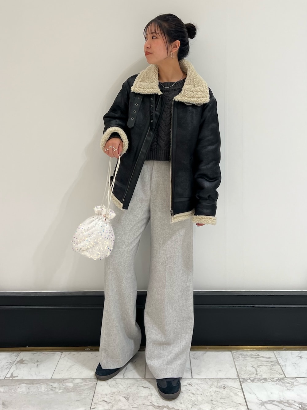 ホワイト系のハンドバッグ、グレー系のニット/セーター、ブラック系のムートンコートを着用したレディースの冬コーディネートの3枚目の写真
