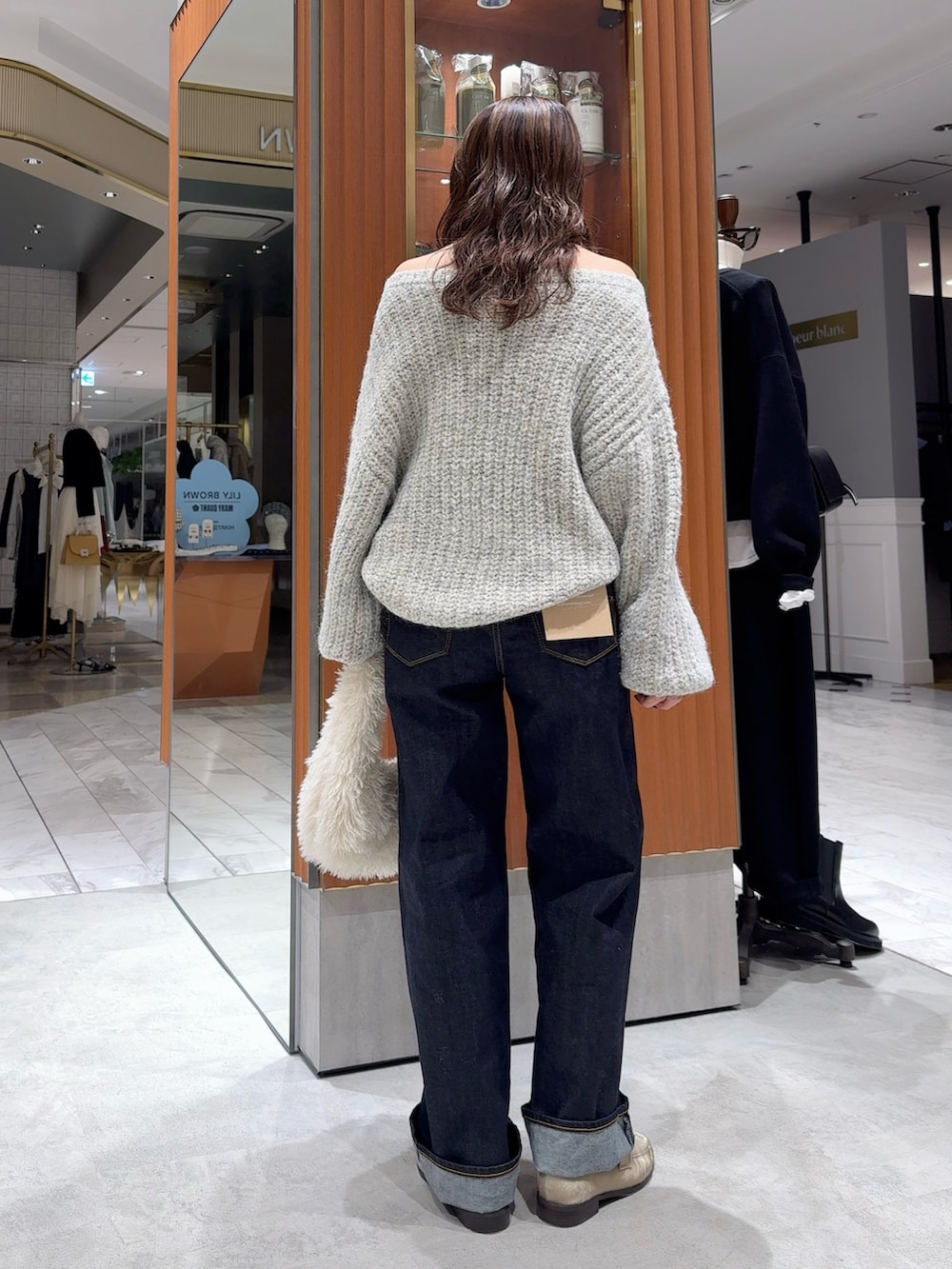 グレー系のニット/セーター、ブルー系のデニムパンツ、ホワイト系のハンドバッグを着用したレディースの冬コーディネートの4枚目の写真