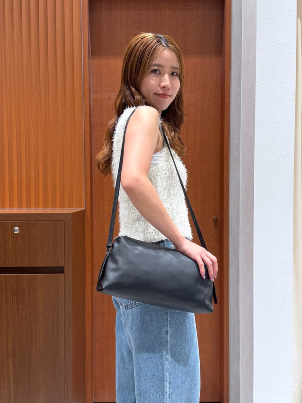 ブルー系のデニムパンツ、ホワイト系のベスト、ブラック系のハンドバッグを着用したレディースの夏コーディネートの8枚目の写真