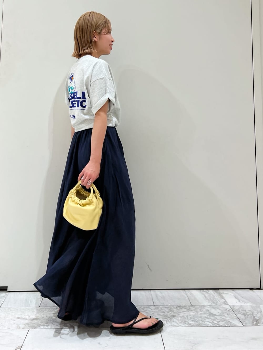 ブラック系のサンダル、ブルー系のスカート、イエロー系のハンドバッグを着用したレディースの春コーディネートの5枚目の写真