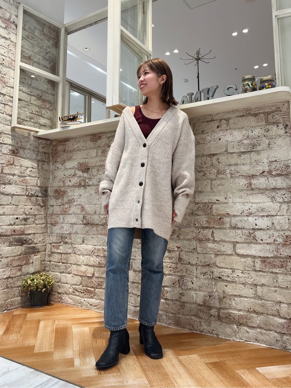 ブラック系のブーツ、ブルー系のデニムパンツ、ホワイト系のカーディガン/ボレロを着用したレディースの秋コーディネートの5枚目の写真