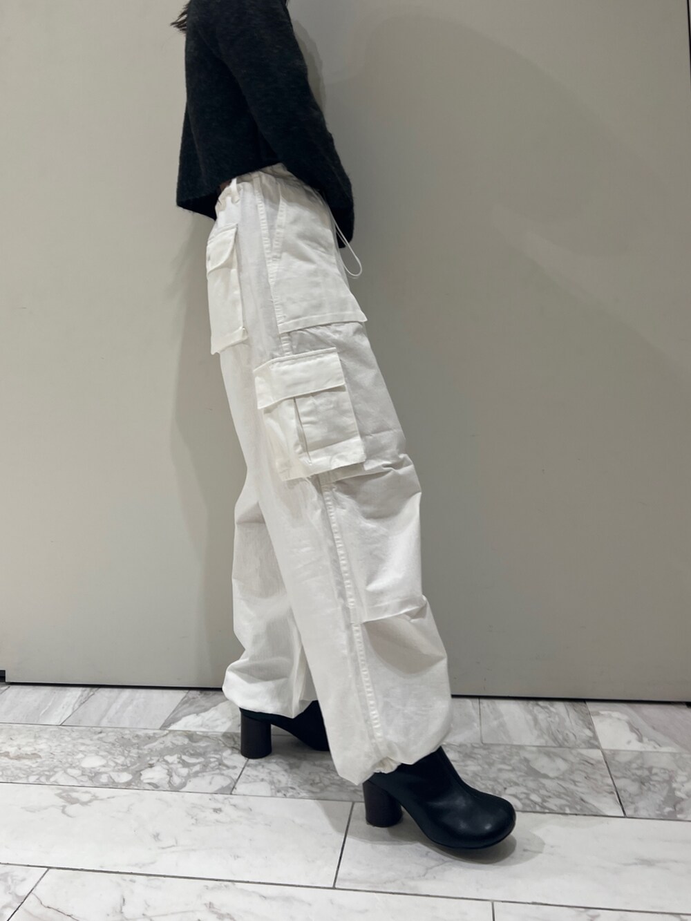 ブラック系のブーツ、ホワイト系のカーゴパンツ、グレー系のニット/セーターを着用したレディースの秋コーディネートの8枚目の写真