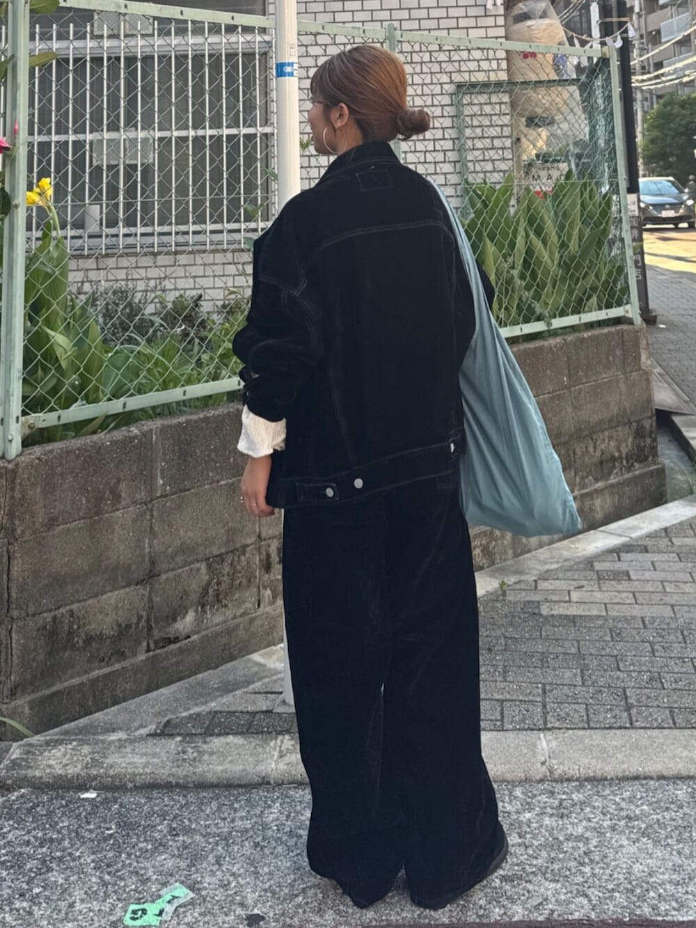 ブラック系のスリッポン、ブラック系のデニムパンツ、ブルー系のトートバッグを着用したレディースの夏コーディネートの4枚目の写真