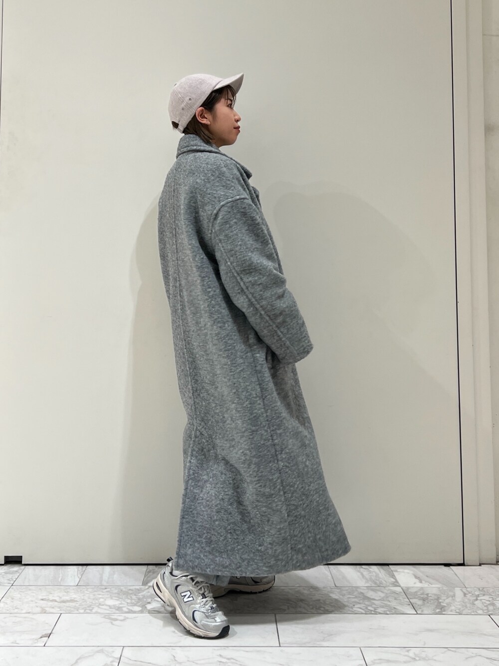 グレー系のチェスターコート、グリーン系のニット/セーター、グレー系のキャップを着用したレディースの冬コーディネートの5枚目の写真