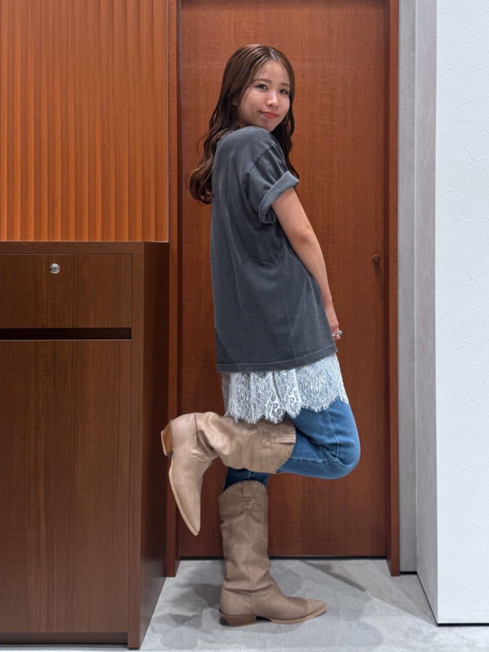 ベージュ系のブーツ、ブルー系のデニムパンツ、ホワイト系のキャミソールを着用したレディースの夏コーディネートの3枚目の写真