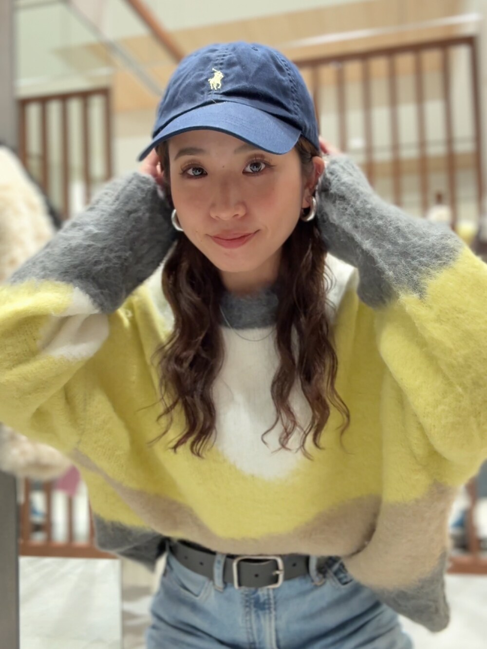 グリーン系のニット/セーター、ブルー系のデニムパンツ、ベージュ系のハンドバッグを着用したレディースの秋コーディネートの3枚目の写真