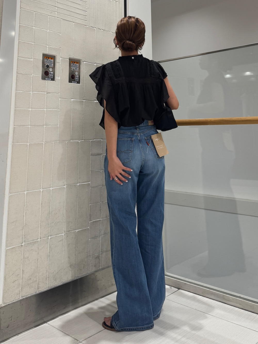 ブルー系のデニムパンツ、ブラック系のシャツ/ブラウス、ブラック系のハンドバッグを着用したレディースの春コーディネートの5枚目の写真