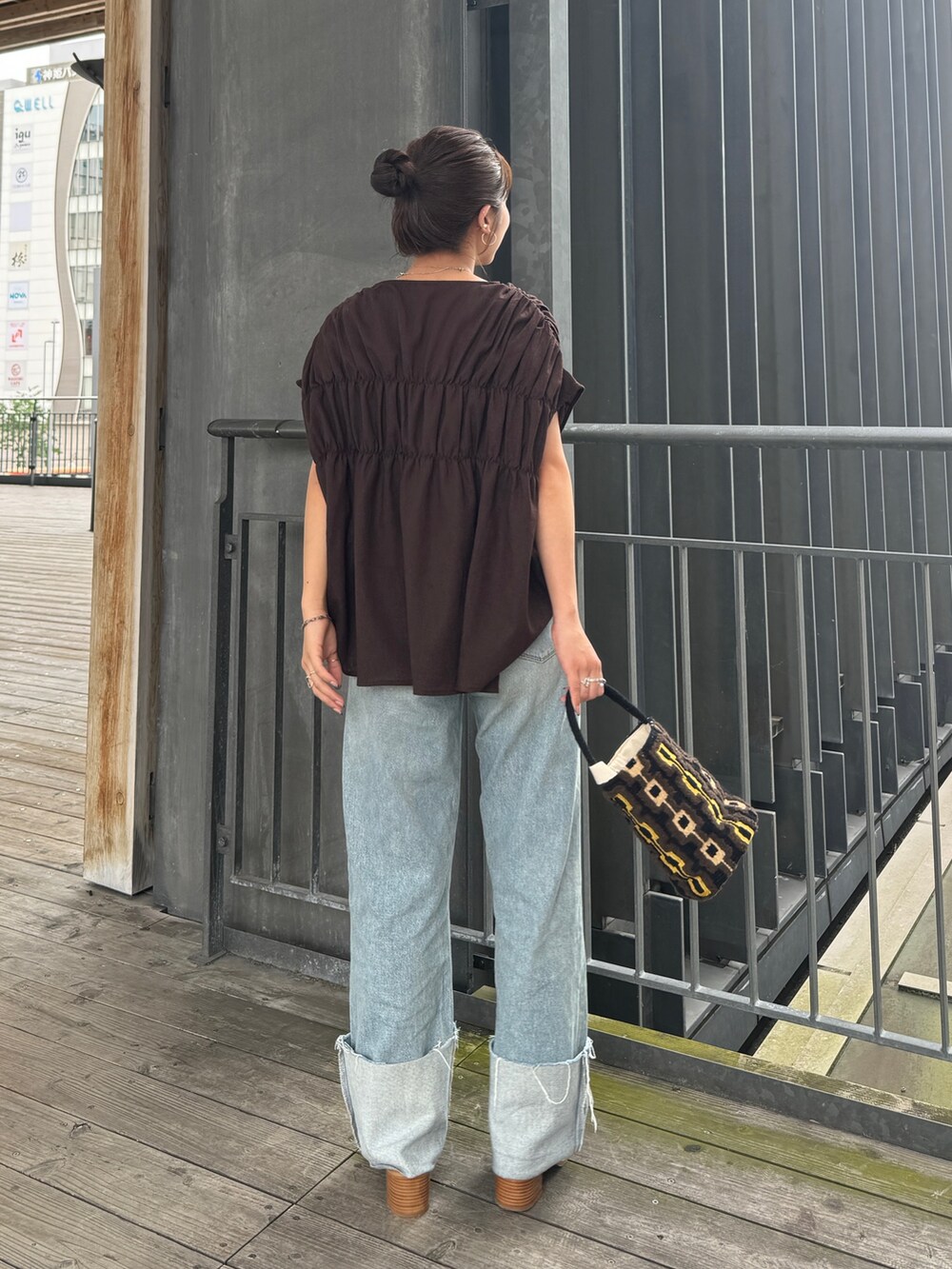 ブルー系のデニムパンツ、ホワイト系のサンダル、ブラウン系のハンドバッグを着用したレディースの夏コーディネートの6枚目の写真